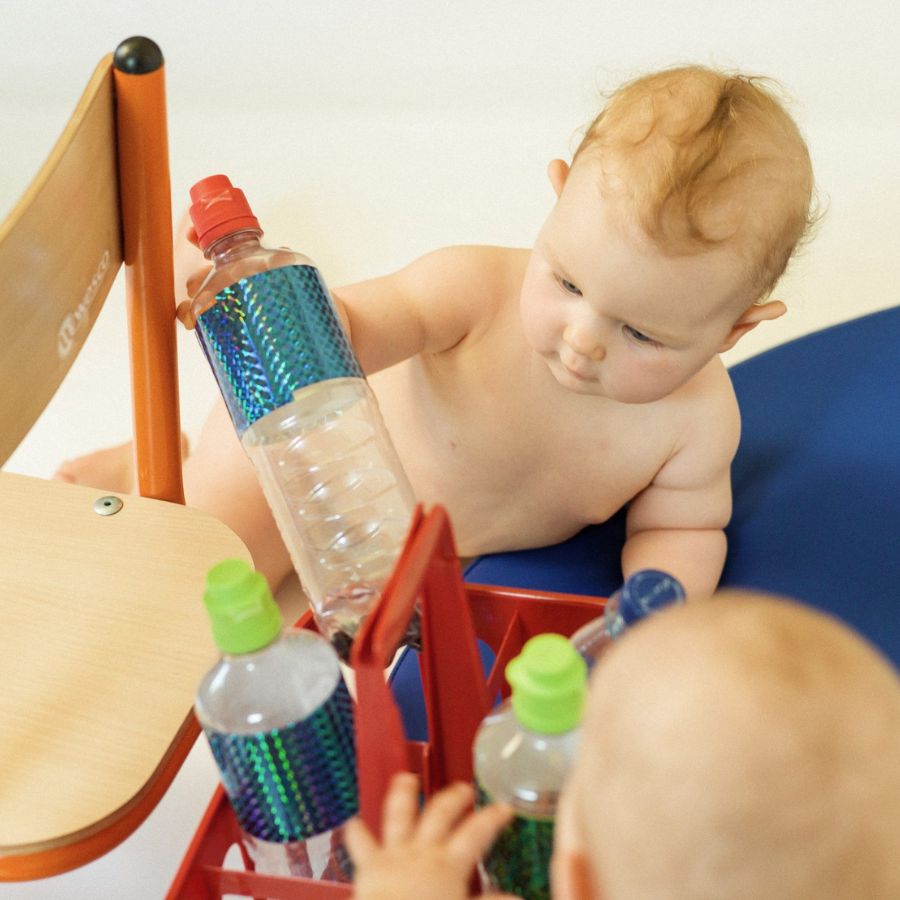 2 Babies spielen in PEKiP Kurs mit Plastikflaschen in der Praxis Nestwärme in München